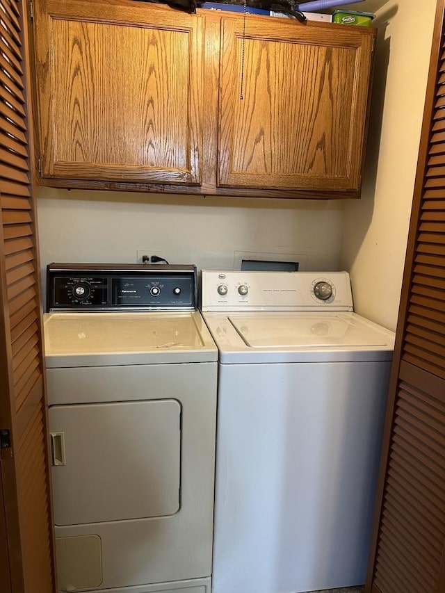 clothes washing area featuring washing machine and clothes dryer and cabinets