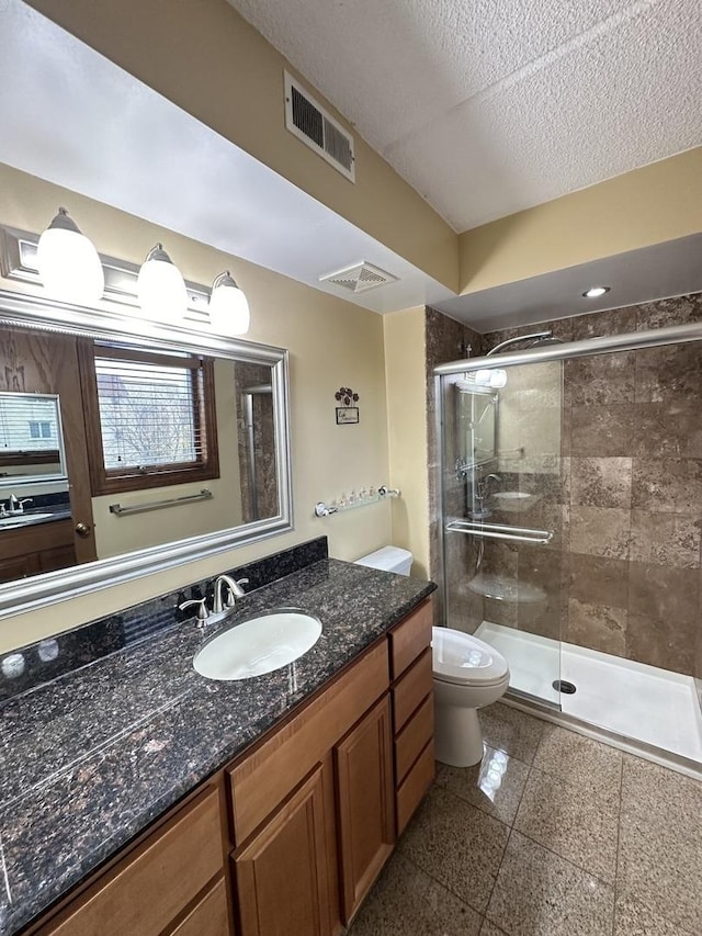 bathroom with a textured ceiling, vanity, an enclosed shower, and toilet