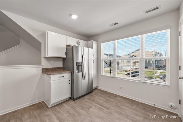 kitchen featuring a wealth of natural light, white cabinetry, light hardwood / wood-style floors, and stainless steel refrigerator with ice dispenser