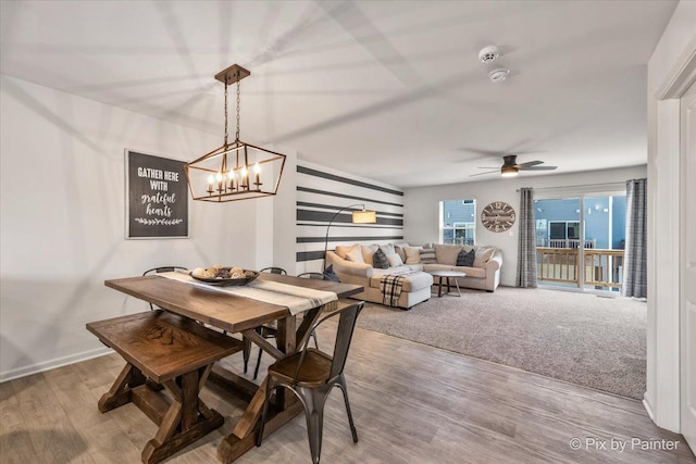 dining room with hardwood / wood-style floors and ceiling fan with notable chandelier