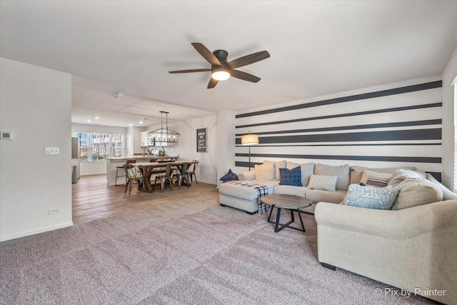 living room with hardwood / wood-style floors and ceiling fan with notable chandelier