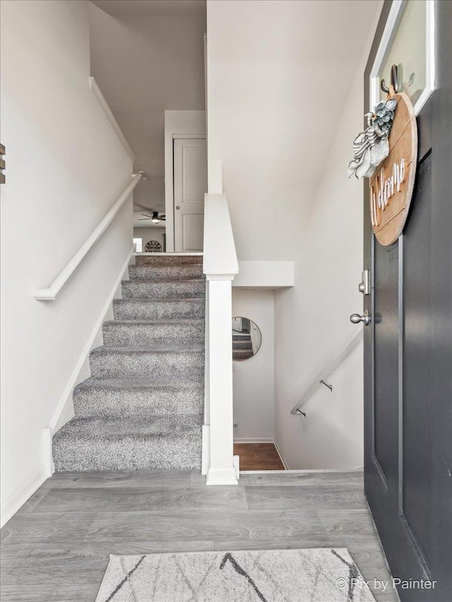 stairway with hardwood / wood-style floors and ceiling fan