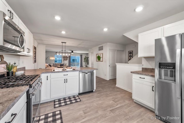 kitchen with kitchen peninsula, appliances with stainless steel finishes, and white cabinetry