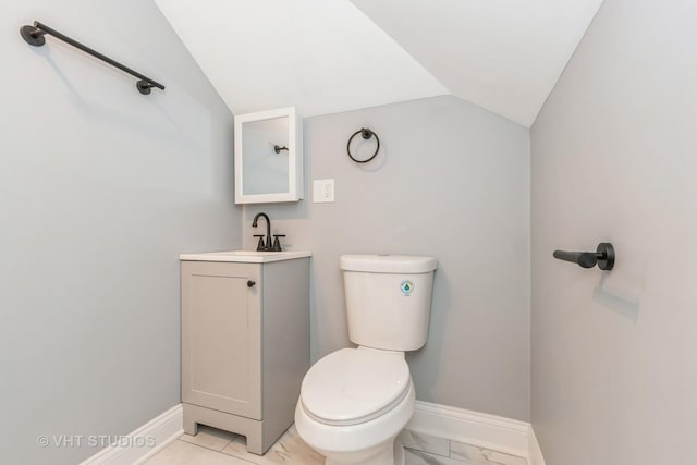 bathroom featuring vanity, toilet, and vaulted ceiling