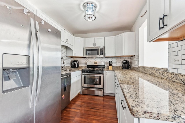 kitchen featuring backsplash, light stone counters, stainless steel appliances, dark hardwood / wood-style floors, and white cabinetry