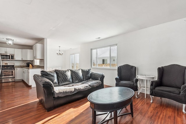 living room featuring a chandelier and dark wood-type flooring