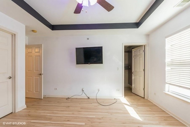 interior space featuring light wood-type flooring, a tray ceiling, and ceiling fan