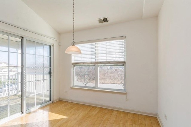 unfurnished dining area with a healthy amount of sunlight, lofted ceiling, and light wood-type flooring