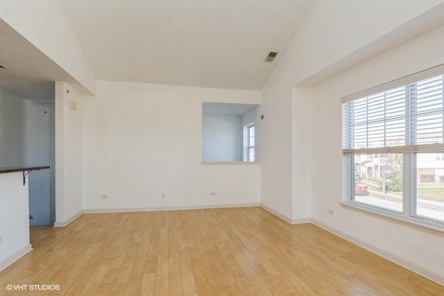 unfurnished room with lofted ceiling and light wood-type flooring