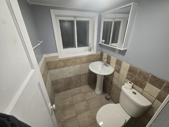 bathroom featuring toilet and tile walls