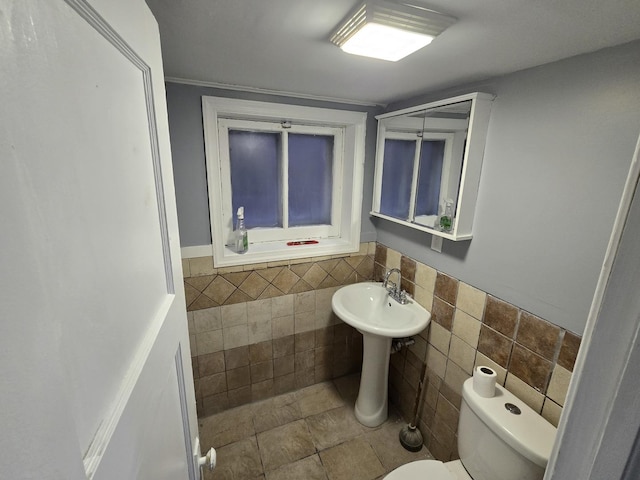 bathroom with toilet and tile walls