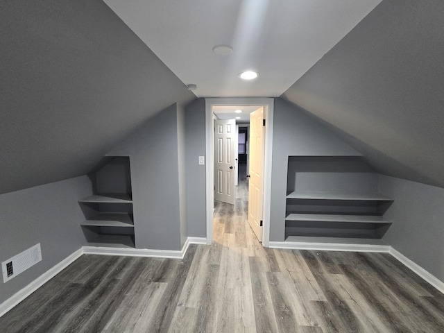 additional living space with dark wood-type flooring and vaulted ceiling