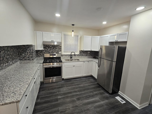 kitchen featuring sink, light stone countertops, appliances with stainless steel finishes, decorative light fixtures, and white cabinetry