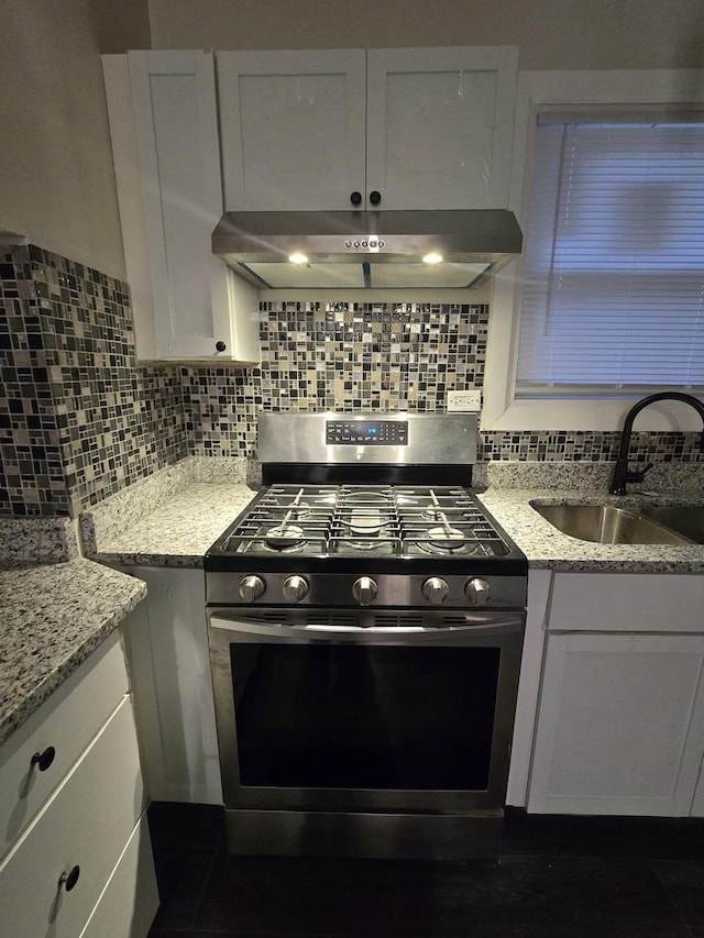 kitchen with stainless steel gas stove, white cabinetry, and sink