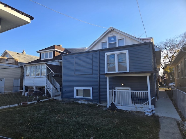 rear view of house featuring covered porch and a lawn