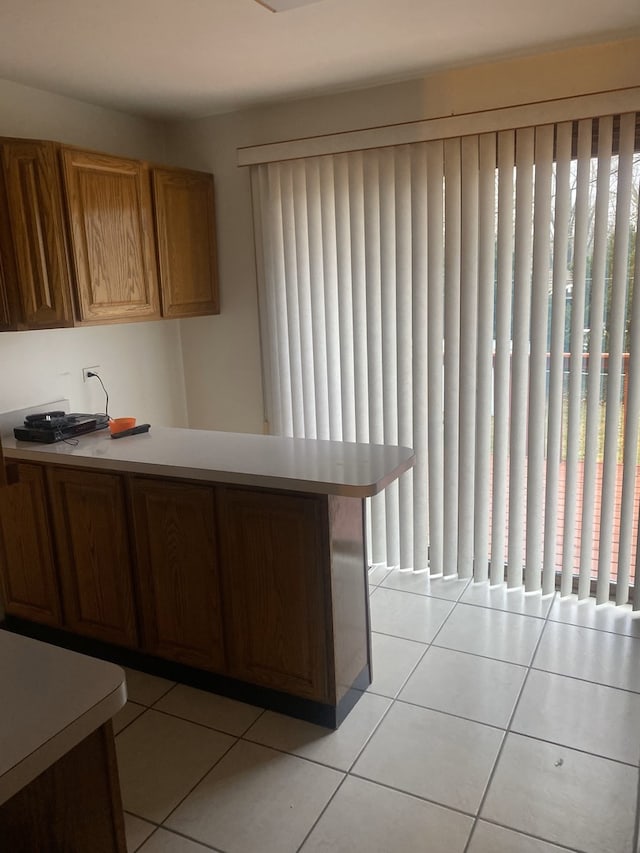 kitchen with kitchen peninsula, light tile patterned floors, and a wealth of natural light