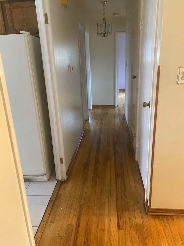 hall featuring hardwood / wood-style flooring and a chandelier