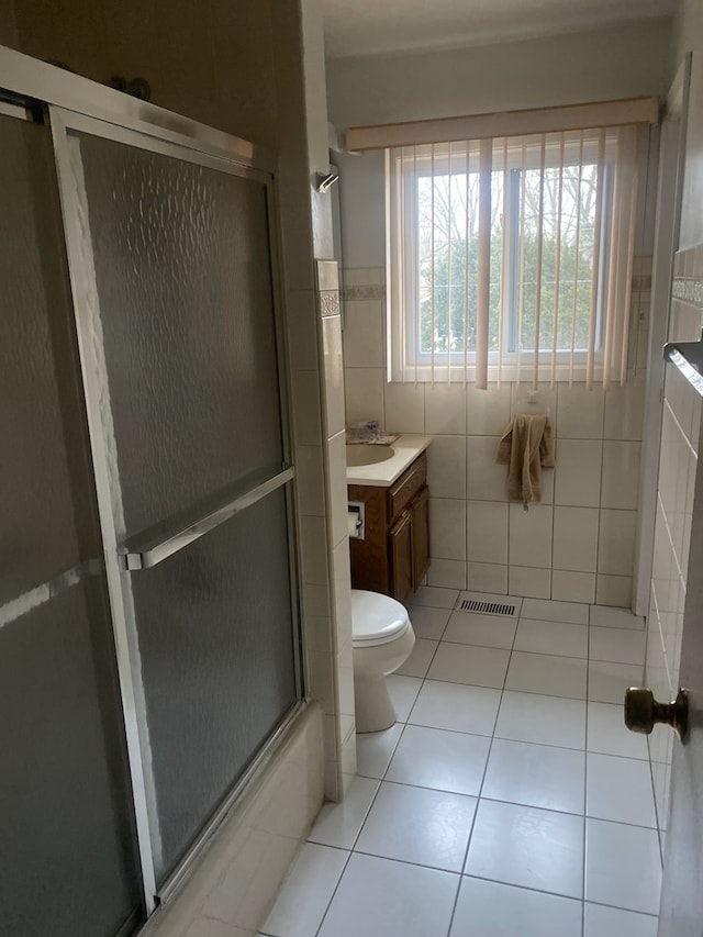 full bathroom featuring vanity, tile walls, enclosed tub / shower combo, tile patterned flooring, and toilet