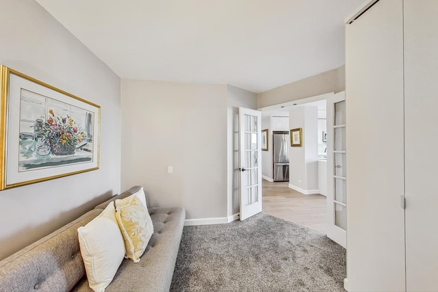 living area featuring french doors, baseboards, and light colored carpet