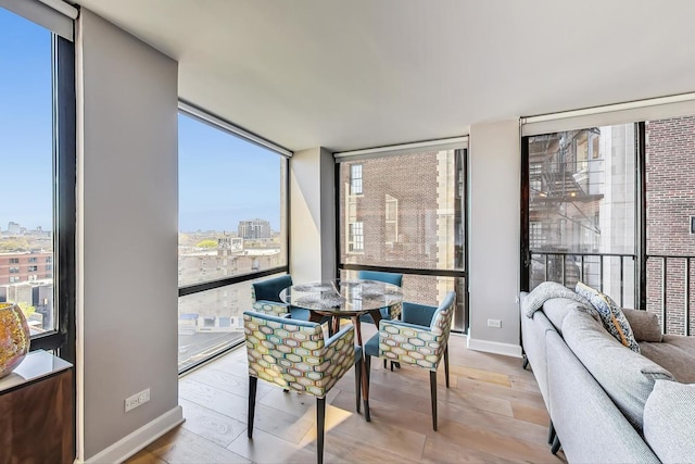 dining space with a city view, floor to ceiling windows, baseboards, and wood finished floors