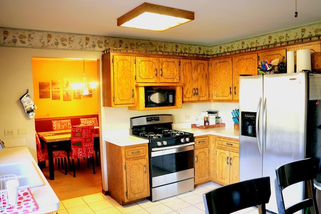 kitchen featuring appliances with stainless steel finishes, sink, light tile patterned floors, pendant lighting, and a chandelier