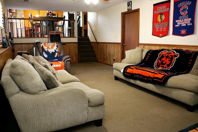 living room featuring carpet floors, ceiling fan, and wood walls