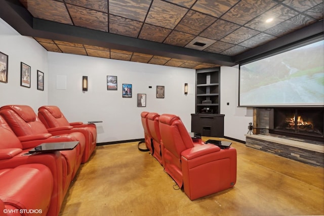 cinema featuring a stone fireplace and concrete floors