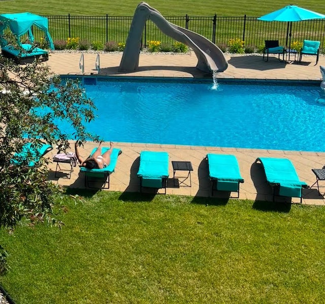 view of swimming pool with a yard and a water slide