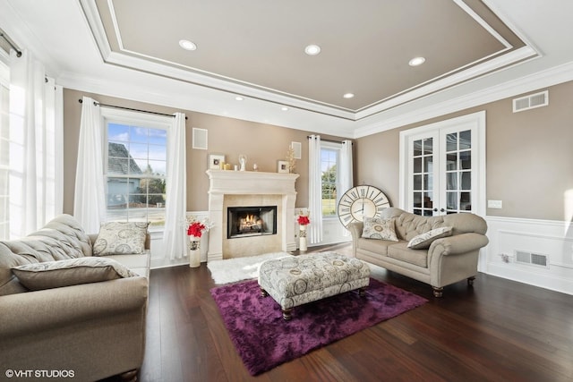 living room with a wealth of natural light, ornamental molding, and a tiled fireplace