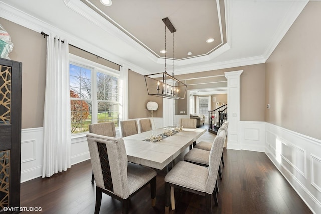 dining area featuring dark hardwood / wood-style flooring, a tray ceiling, ornate columns, and crown molding