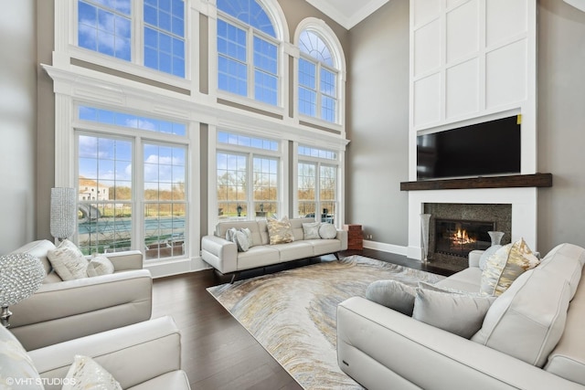 living room featuring crown molding, dark wood-type flooring, and a high ceiling