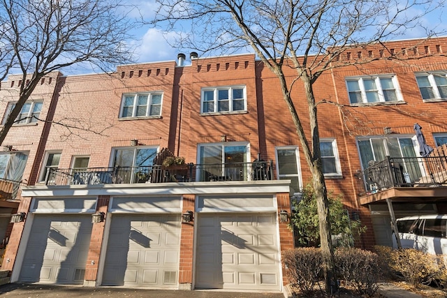 rear view of property featuring a balcony and a garage