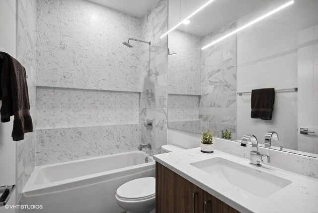 full bathroom featuring tiled shower / bath combo, toilet, and vanity