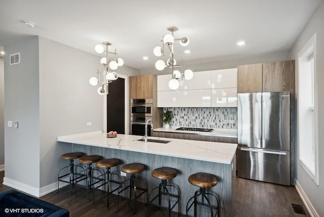 kitchen featuring a kitchen breakfast bar, stainless steel appliances, sink, dark hardwood / wood-style floors, and white cabinetry