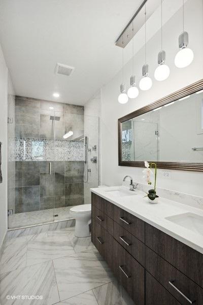 bathroom featuring vanity, toilet, and a shower with door