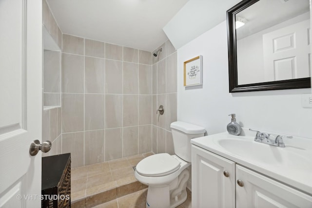 bathroom with tile patterned flooring, a tile shower, vanity, and toilet