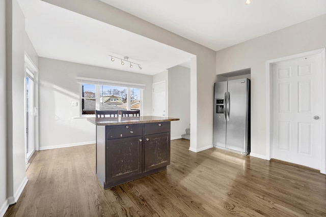 kitchen with dark hardwood / wood-style flooring, stainless steel fridge, dark brown cabinets, and a center island