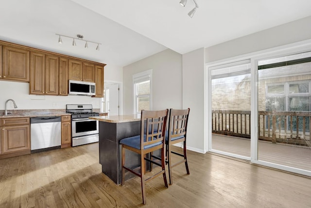 kitchen with light stone counters, light hardwood / wood-style flooring, stainless steel appliances, and sink