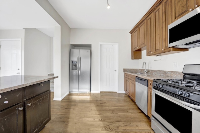 kitchen with light stone counters, sink, hardwood / wood-style floors, and appliances with stainless steel finishes