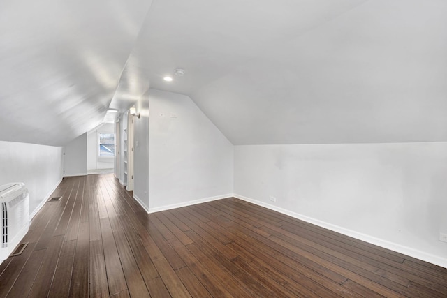 additional living space featuring dark wood-type flooring and vaulted ceiling