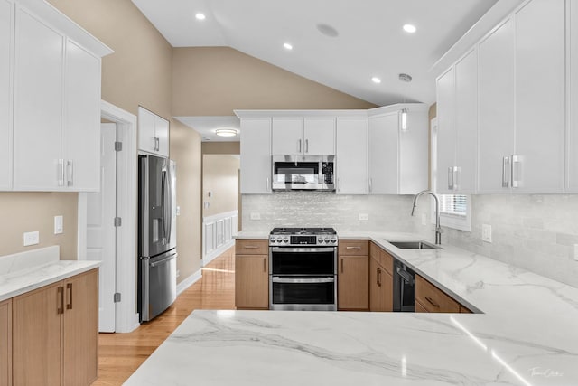 kitchen featuring light stone countertops, white cabinetry, sink, stainless steel appliances, and light wood-type flooring