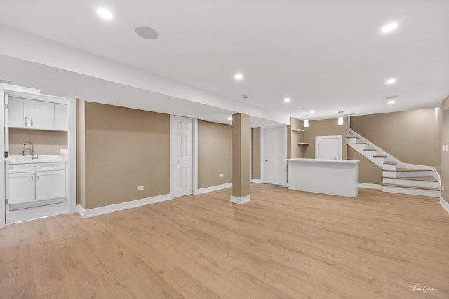 basement featuring light wood-type flooring and sink