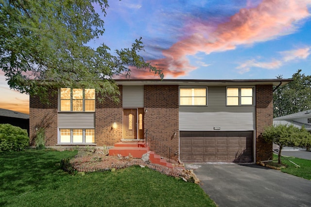 bi-level home featuring a garage and a lawn