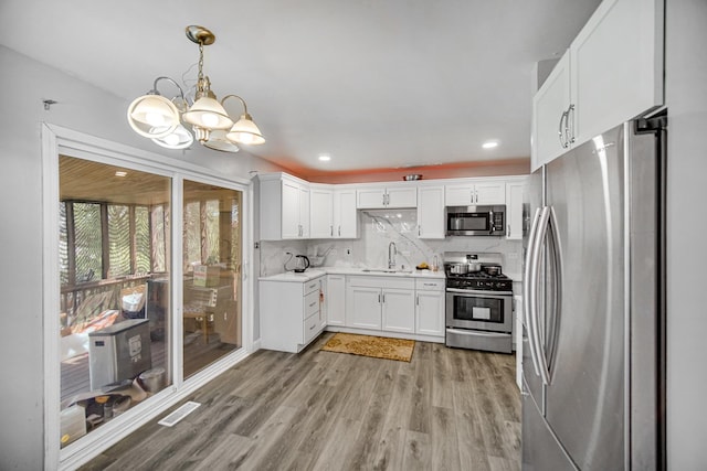 kitchen with white cabinetry, sink, light hardwood / wood-style flooring, backsplash, and appliances with stainless steel finishes