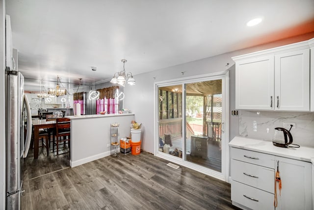 kitchen with white cabinetry, tasteful backsplash, dark hardwood / wood-style floors, stainless steel fridge, and pendant lighting