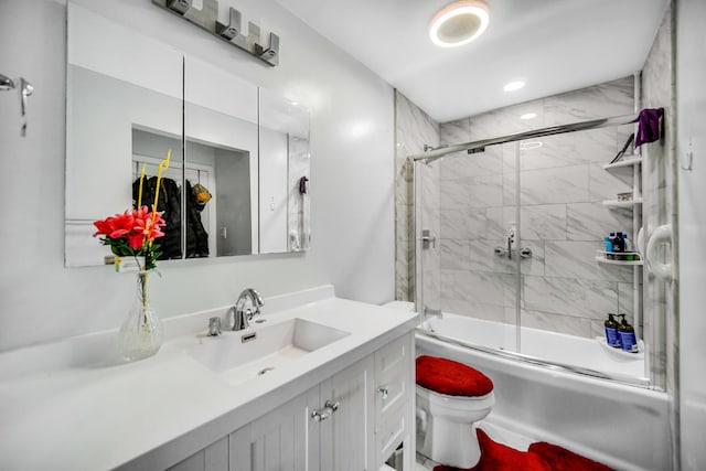 full bathroom featuring toilet, combined bath / shower with glass door, and vanity