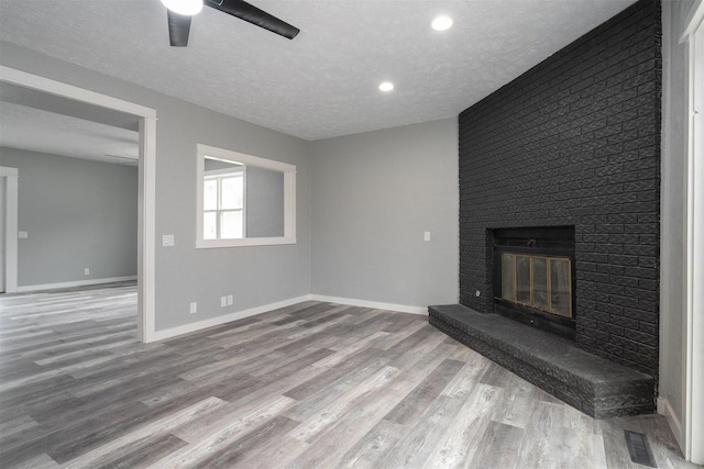 unfurnished living room featuring a fireplace, ceiling fan, hardwood / wood-style floors, and a textured ceiling