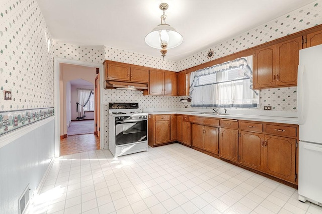 kitchen with tasteful backsplash, hanging light fixtures, white appliances, and sink