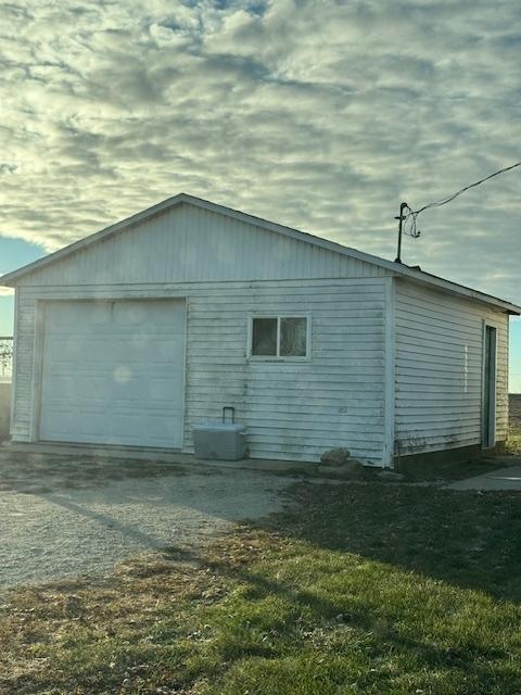 property exterior at dusk featuring a garage and an outbuilding