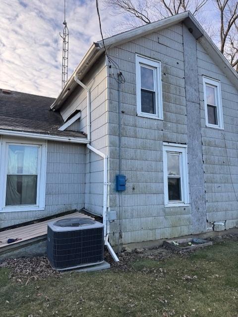 view of side of property with a lawn and central AC